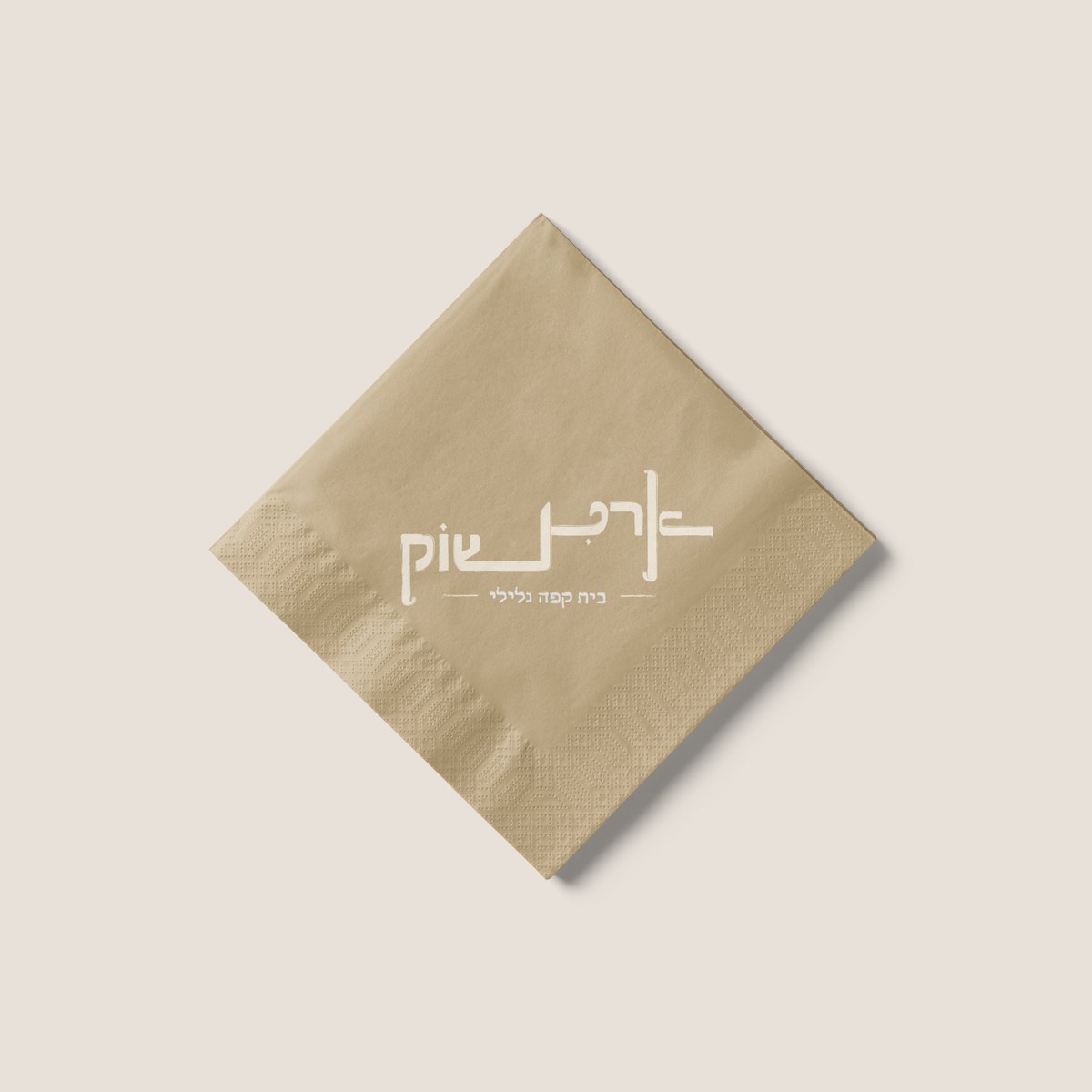 A folded kraft-colored napkin printed with the white, reversed Artichoke wordmark