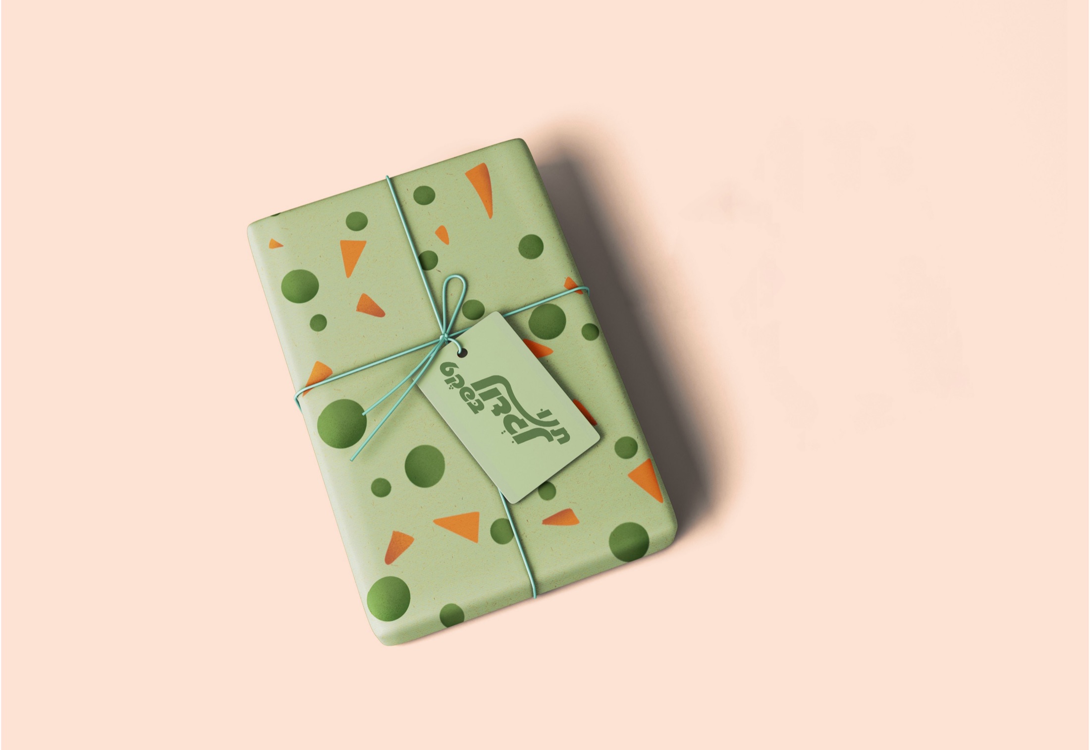 A wrapped gift box in the brand's green dot-and-triangle pattern, tied with string and a small logo tag